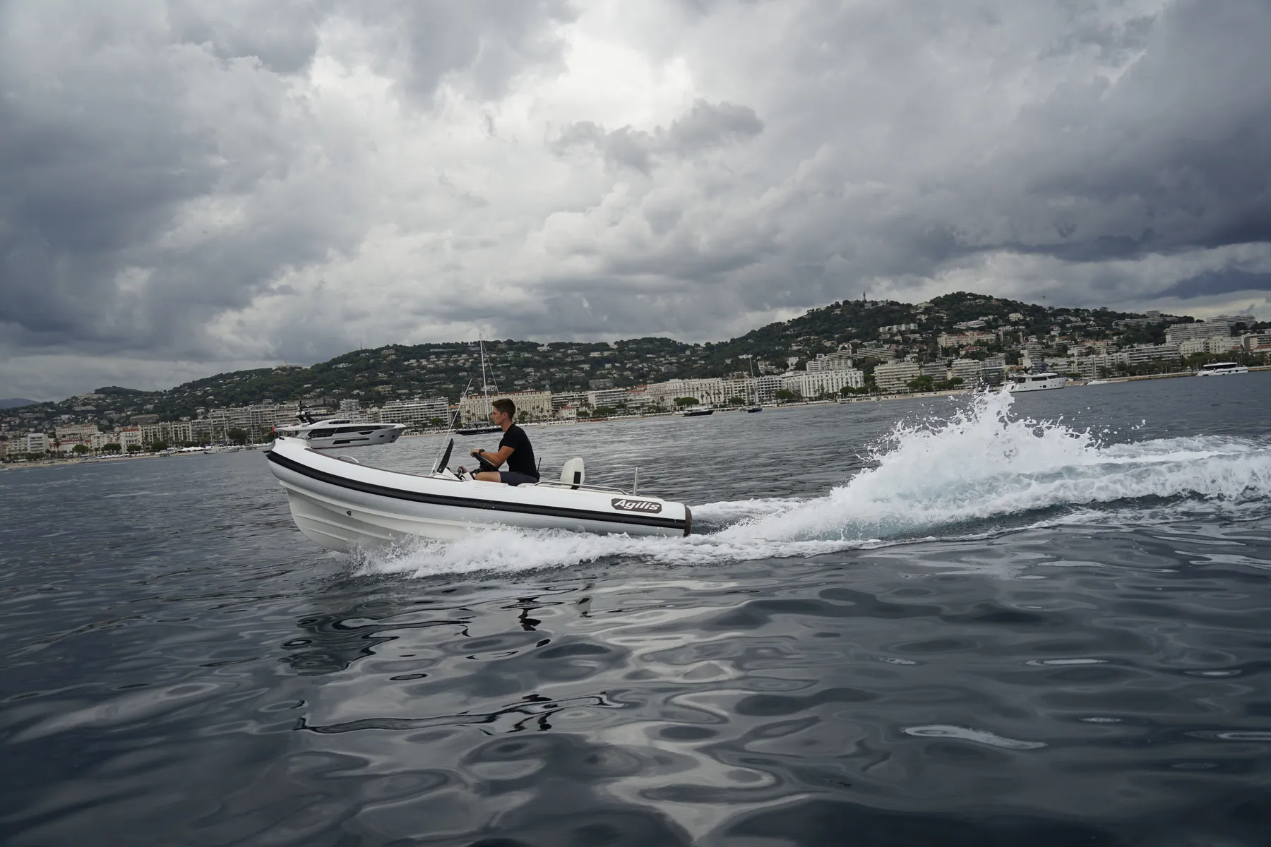 Agilis jet tender running along a Mediterranean seafront under heavy clouds