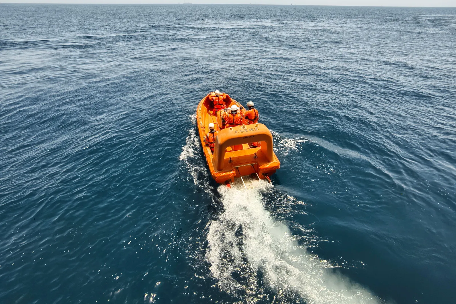 Fast rescue boat with crew in survival suits under way on open sea